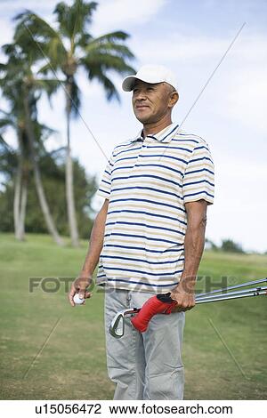 Stock Image - Mature man standing on golf course. Fotosearch