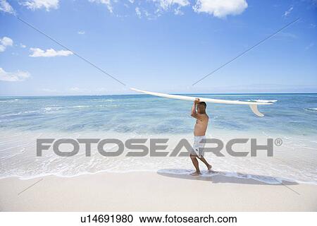Stock Image - Mature man walking with surfboard. Fotosearch