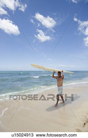 Stock Image - Mature man walking with surfboard. Fotosearch