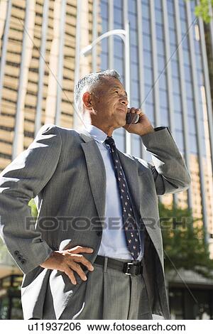 Stock Photograph - Profile of a businessman using mobile phone. Fotosearch