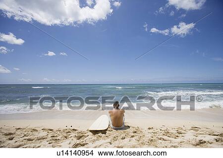 Picture - Rear view of a man sitting at beach. Fotosearch