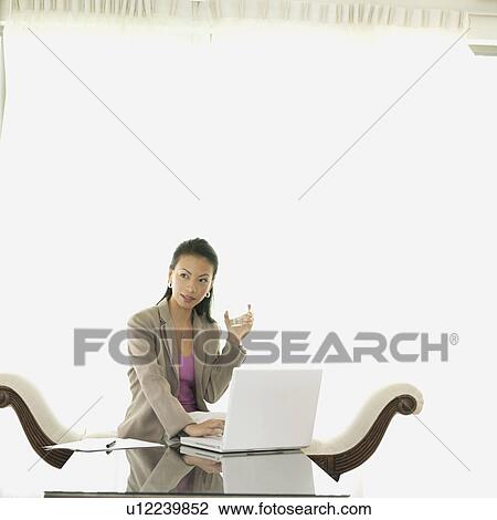 Businesswoman holding a glass of water View Large Photo Image Stock Image - Businesswoman holding a glass of water. Fotosearch
