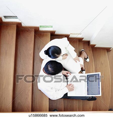 Stock Photography - High angle view of a businessman and businesswoman sitting together on a staircase. Fotosearch