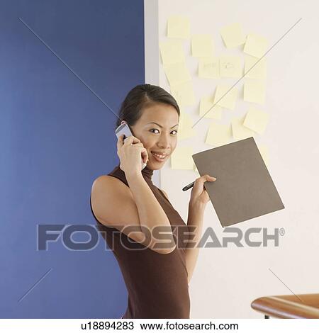 Stock Image - Portrait of a young woman talking on a mobile phone. Fotosearch