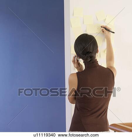 Stock Image - Rear view of a young woman talking on a mobile phone. Fotosearch