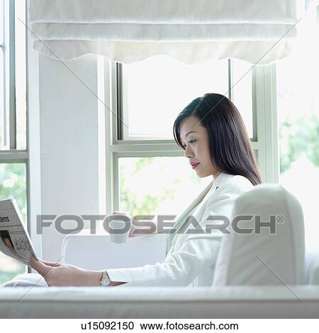 Stock Image - Side profile of a businesswoman reading a newspaper. Fotosearch