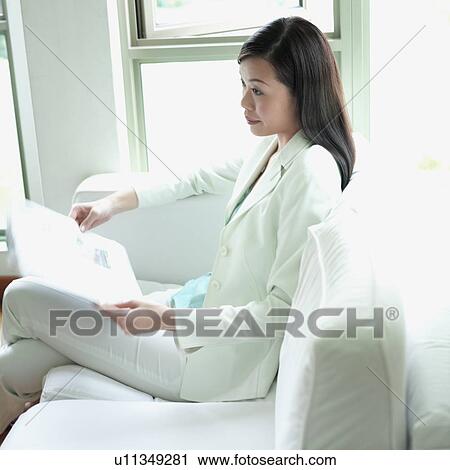Side profile of a businesswoman sitting with a newspaper in her hand View Large Photo Image Stock Image - Side profile of a businesswoman sitting with a newspaper in her hand. Fotosearch