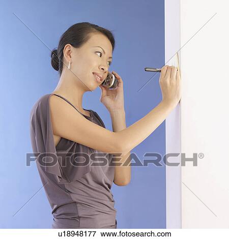 Stock Photo - Side profile of a young woman talking on a mobile phone. Fotosearch