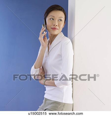 Stock Photography - Side profile of a young woman talking on a mobile phone. Fotosearch