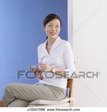Stock Photo - Young woman holding a personal data assistant. Fotosearch