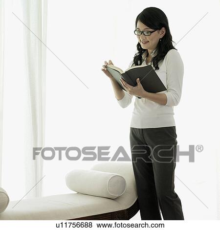 Young woman standing and reading a book View Large Photo Image Stock Photo - Young woman standing and reading a book. Fotosearch