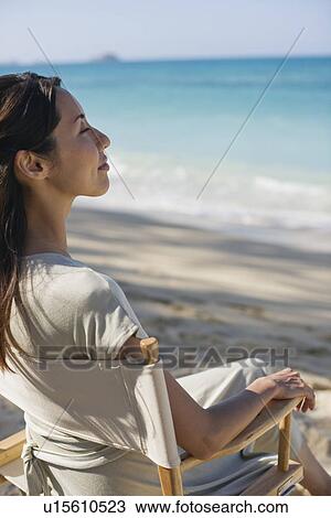 A young woman sitting on chair at beach View Large Photo Image Stock Image - A young woman sitting on chair at beach. Fotosearch