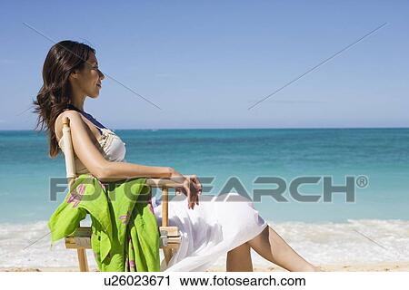 A young woman sitting on chair at beach View Large Photo Image Stock Image - A young woman sitting on chair at beach. Fotosearch
