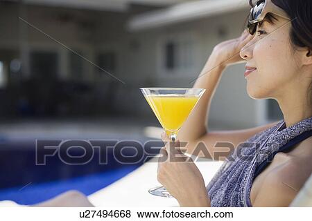 Stock Photo - A young woman sitting with drinks. Fotosearch