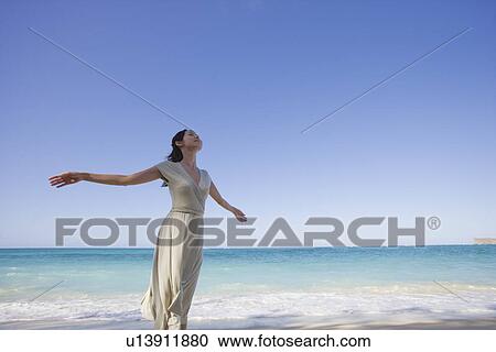 Stock Image - A young woman standing on beach. Fotosearch