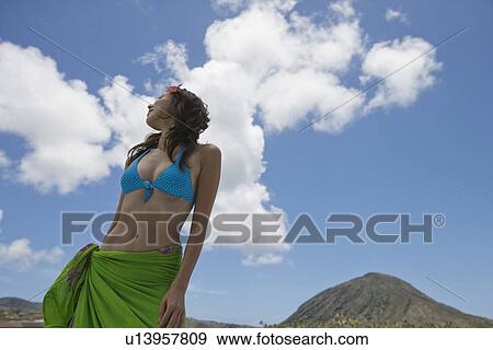 Low angle view of a young woman standing under cloudy sky View Large Photo Image Stock Photo - Low angle view of a young woman standing under cloudy sky. Fotosearch