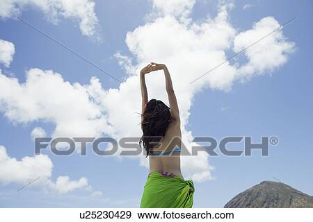 Stock Photo - Rear view of a woman with hands raised. Fotosearch
