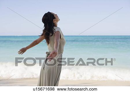 Side view of a young woman standing on beach View Large Photo Image Stock Photo - Side view of a young woman standing on beach. Fotosearch