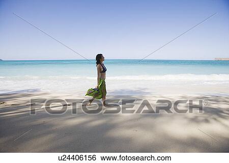 Side view of a young woman walking on beach View Large Photo Image Stock Photograph - Side view of a young woman walking on beach. Fotosearch