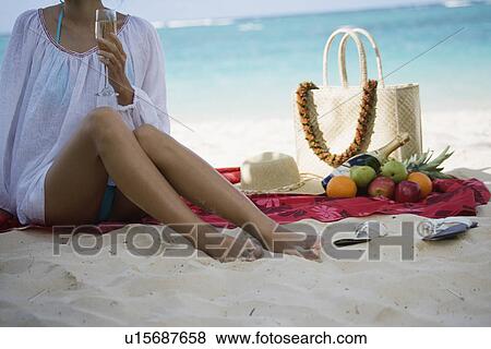 Stock Photo - A woman holding wineglass at beach. Fotosearch