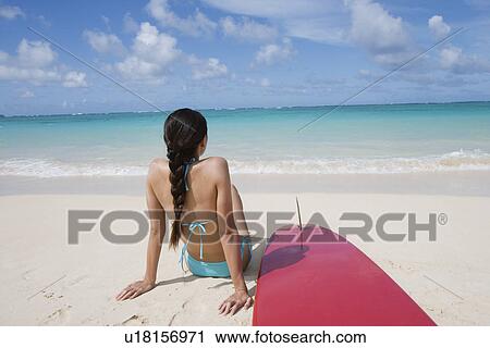 A woman sitting on beach with surfboard View Large Photo Image Stock Image - A woman sitting on beach with surfboard. Fotosearch