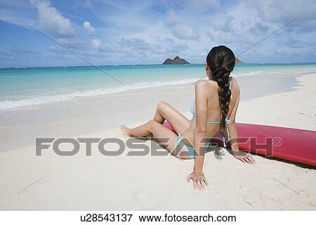 A woman sitting on beach with surfboard View Large Photo Image Stock Photo - A woman sitting on beach with surfboard. Fotosearch