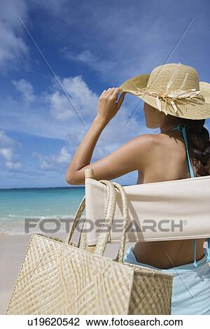 Stock Image - A woman sitting on chair on beach. Fotosearch
