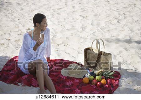 Elevated view of a young woman holding wineglass at beach View Large Photo Image Stock Image - Elevated view of a young woman holding wineglass at beach. Fotosearch