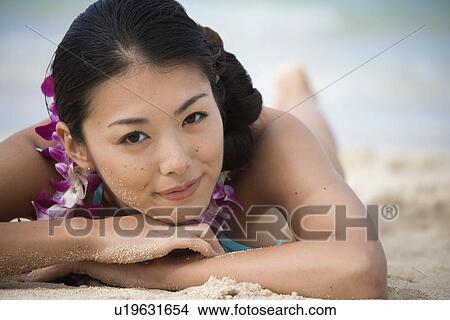 Picture - Portrait of a young woman lying at beach. Fotosearch