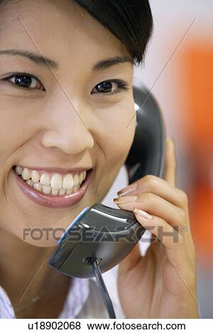 Stock Photo - A portrait of a woman conversing on the telephone. Fotosearch