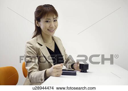 Picture - A woman holding a cup of coffee as she smiles at the camera. Fotosearch