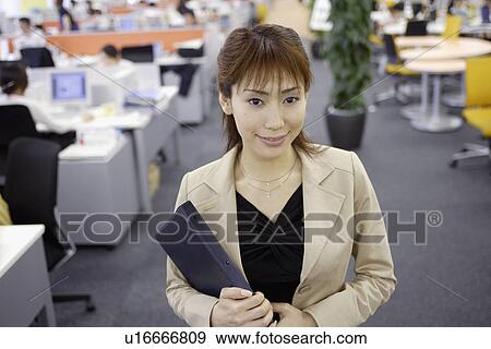 Stock Photo - A woman holding a diary smiles at the camera. Fotosearch