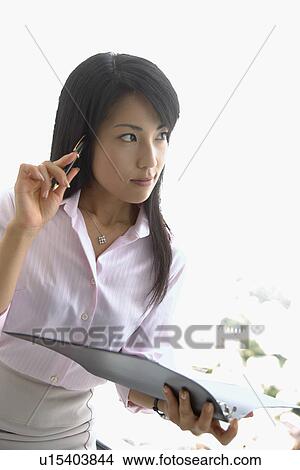 Picture - A woman holding a file lost in her thoughts. Fotosearch