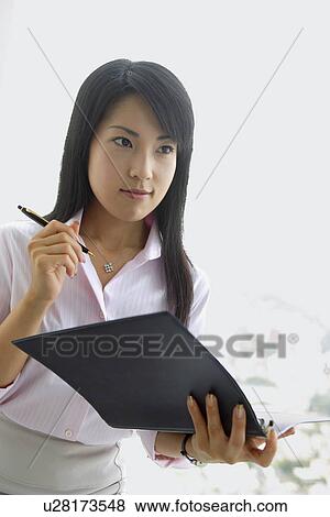 A woman holding a file stares at something View Large Photo Image Stock Photo - A woman holding a file stares at something. Fotosearch