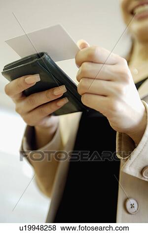 Stock Photo - A woman reading a note on the card as she holds a diary. Fotosearch