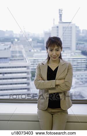 Stock Image - A woman standing against large sliding windows. Fotosearch