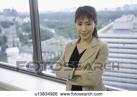 Stock Photograph - A woman standing against large sliding windows. Fotosearch