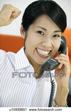 Stock Image - An ecstatic woman showing her emotions while conversing on the telephone,. Fotosearch