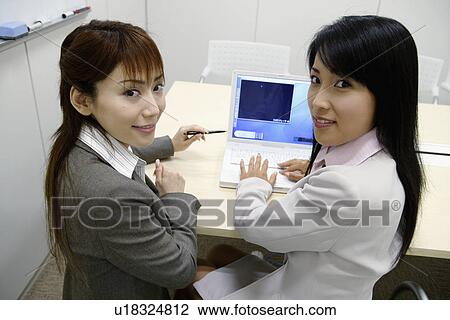 Two businesswomen working on the laptop View Large Photo Image Stock Image - Two businesswomen working on the laptop. Fotosearch