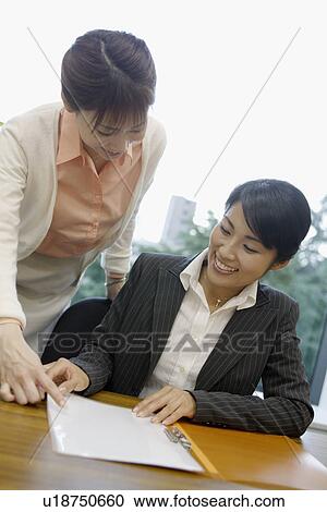 Two women exchange happiness as they look over the file View Large Photo Image Stock Image - Two women exchange happiness as they look over the file. Fotosearch