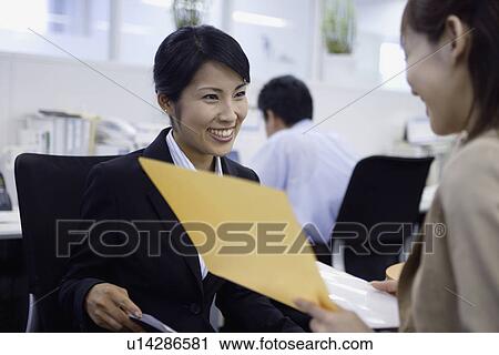 Stock Image - Two women expresses their happiness on looking over the documents. Fotosearch