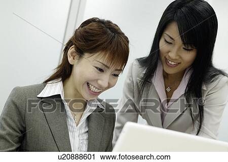 Stock Image - Two women in ecstasy as they look over the laptop. Fotosearch
