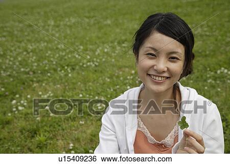 Portrait of a young woman holding a plant View Large Photo Image Stock Photograph - Portrait of a young woman holding a plant. Fotosearch