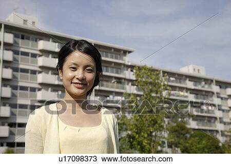 Portrait of a young woman smiling with buildings in background View Large Photo Image Stock Image - Portrait of a young woman smiling with buildings in background. Fotosearch