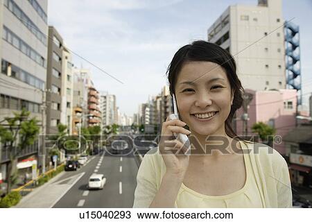 Stock Image - Portrait of a young woman talking on mobile phone. Fotosearch