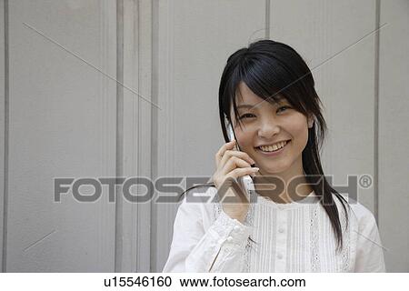 Stock Image - Portrait of a young woman talking on mobile phone. Fotosearch
