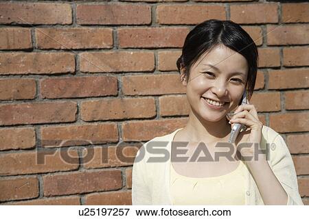 Stock Photo - Portrait of a young woman talking on mobile phone. Fotosearch