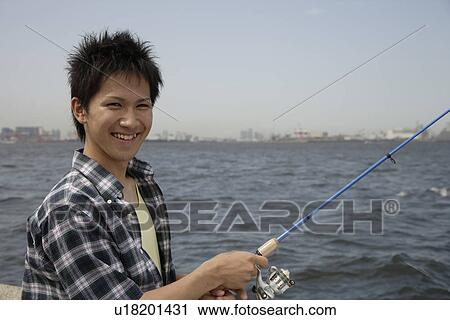 Portrait of a young man holding a fishing rod View Large Photo Image Stock Image - Portrait of a young man holding a fishing rod. Fotosearch