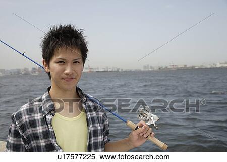Stock Photography - Portrait of a young man holding a fishing rod. Fotosearch