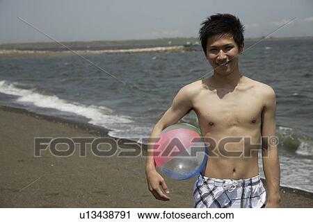 Portrait of a young man holding ball on beach View Large Photo Image Stock Image - Portrait of a young man holding ball on beach. Fotosearch